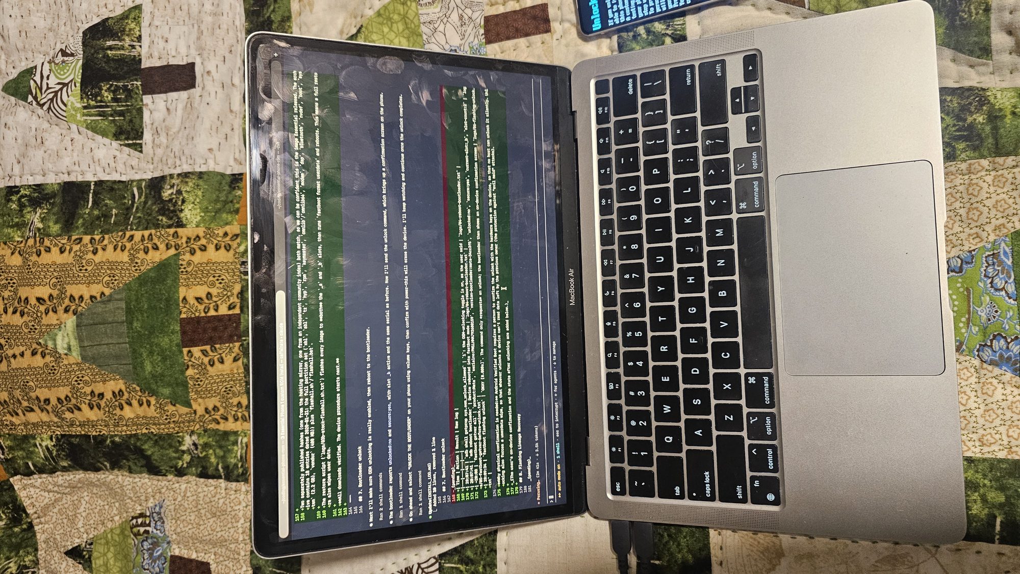 Overhead view of a MacBook Air running Claude Code, with the install log being edited in the terminal